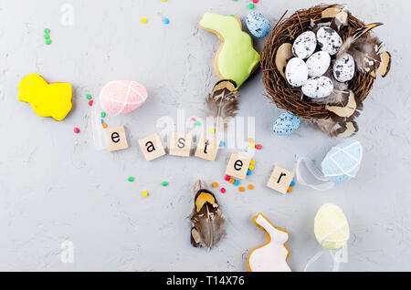 Easter colorful gingerbread cookies,  small decorative eggs in the nest and tulips on light grey concrete background, top view,  copy space, Easter gr Stock Photo