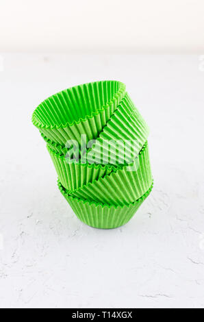 Brightly green colored paper baking cups for cupcakes or muffins on light grey conkrete background, copy space Stock Photo