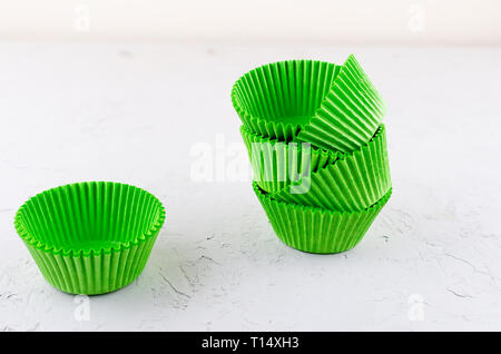 Brightly green colored paper baking cups for cupcakes or muffins on light grey conkrete background, copy space Stock Photo