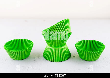 Brightly green colored paper baking cups for cupcakes or muffins on light grey conkrete background, copy space Stock Photo