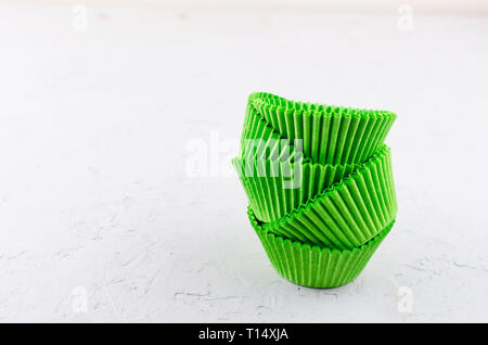 Brightly green colored paper baking cups for cupcakes or muffins on light grey conkrete background, copy space Stock Photo