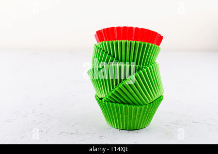 Brightly green and red colored paper baking cups for cupcakes or muffins on light grey conkrete background, copy space Stock Photo