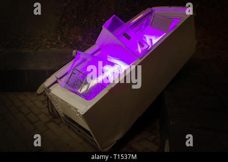 A creative art concept on the light exhibition in Spain. An old broken fridge glowing from inside with violet. Recycing concept of modern contemporary Stock Photo