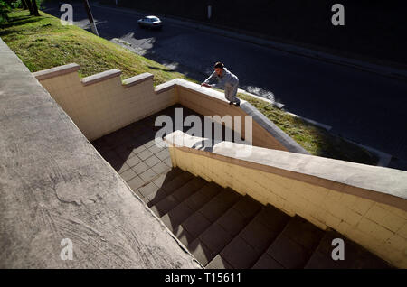 A young guy performs a jump through the space between the concrete parapets. The athlete practices parkour, training in street conditions. The concept Stock Photo