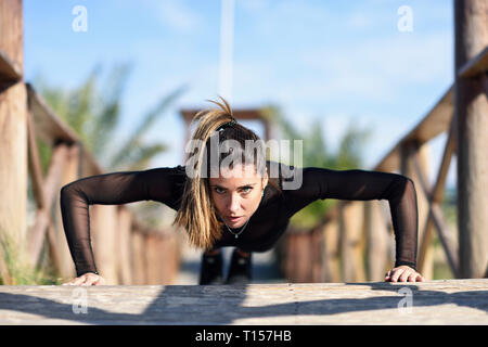 Sportive woman doing push-ups on wooden bridge Stock Photo