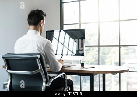 Businessman in office working on computer in front of window Stock Photo