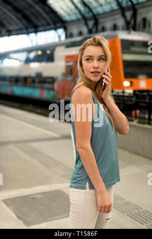 Young woman on cell phone at the train station looking around Stock Photo