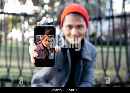Young man showing mobile phone with portrait of himself Stock Photo
