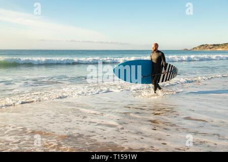 Spain, Andalusia, Tarifa, man walking with stand up paddle board at the sea Stock Photo