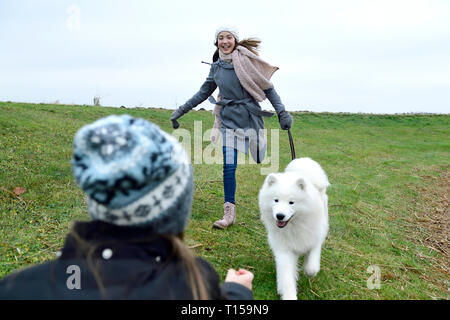 Two girls having fun with dog outdoors Stock Photo