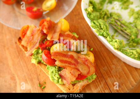 Overhead of open-faced sandwich with cherry tomatoes, mashed avocado and bacon Stock Photo