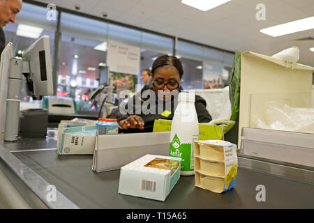Waitrose supermarket checkout counter food kefir, hummus, older black female grocery store worker working on till in London England UK  KATHY  DEWITT Stock Photo
