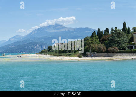 Stony Beach of Sirmione town on Garda Lake with view of Grottoes of Catullus (Grotte di Catullo), the ruins of a Roman villa built at the end of the 1 Stock Photo