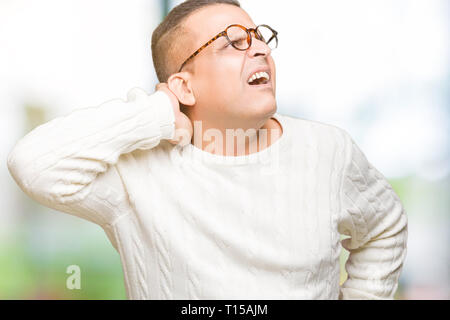 Middle age arab man wearing glasses over isolated background Suffering of neck ache injury, touching neck with hand, muscular pain Stock Photo