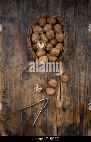 Wickerbasket of walnuts and nutcracker on wood Stock Photo