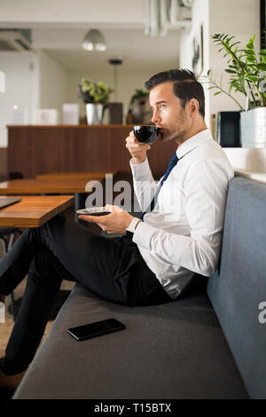 Businessman enjoying coffee and having a break on bench in cafe Stock Photo