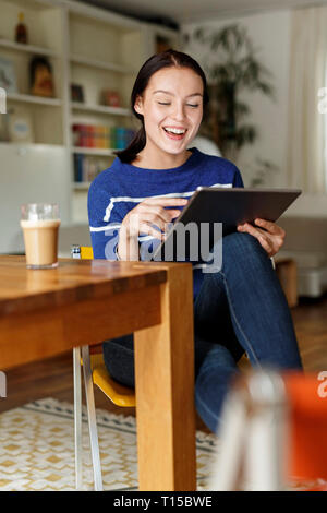 Young woman sitting at home, using digital tablet Stock Photo