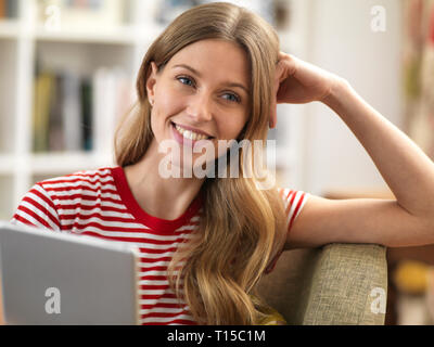 Smiling young woman relaxing at home using a tablet Stock Photo
