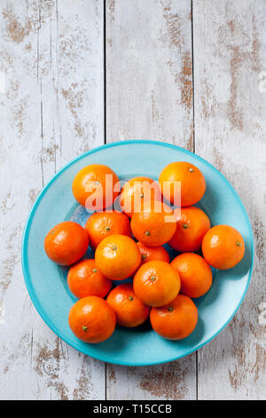 Tangerines on blue plate on wooden background Stock Photo