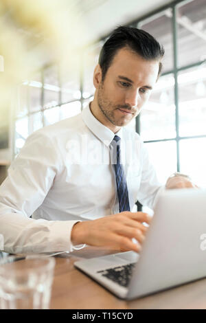 Young businessman working on laptop in cafe on wooden table Stock Photo