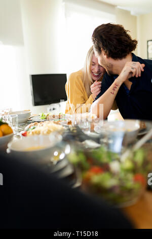 Friends having lunch together, affectionate couple kissing at the table Stock Photo