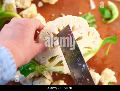 A woman cuts up a fresh cauliflower Stock Photo