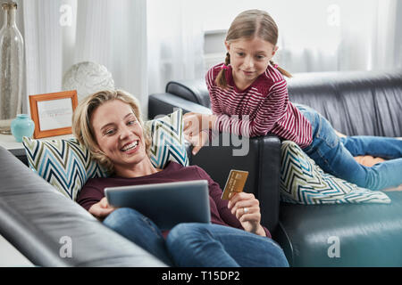 Happy mother and daughter shopping online on couch at home Stock Photo
