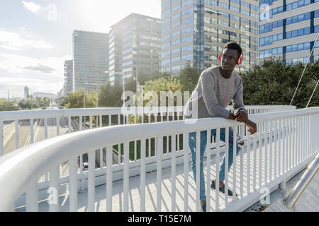 Young man standing on a bridge, listening music Stock Photo