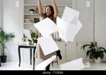 Relieved young woman throwing blank sheets of paper in the air Stock Photo