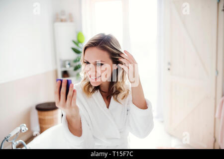 Smiling woman in bathrobe looking in mirror in the morning at home Stock Photo