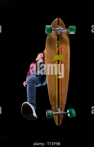 Happy young woman driving longboard seen from below Stock Photo