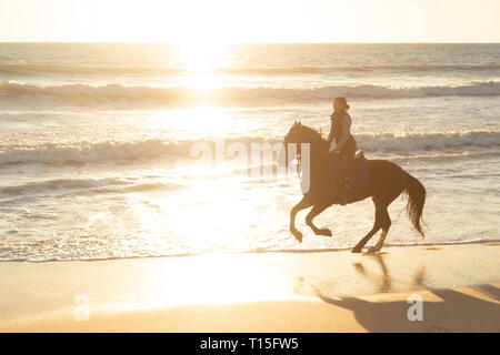 Spain, Tarifa, woman riding horse on the beach at sunset Stock Photo