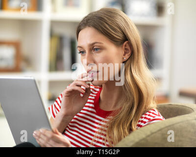 Young woman relaxing at home using a tablet Stock Photo