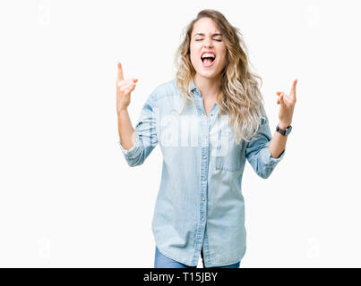Beautiful young blonde woman over isolated background shouting with crazy expression doing rock symbol with hands up. Music star. Heavy concept. Stock Photo