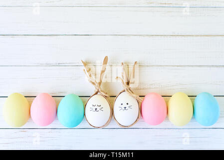 Colorful easter eggs with painted faces and bunny ears in row on white background Stock Photo