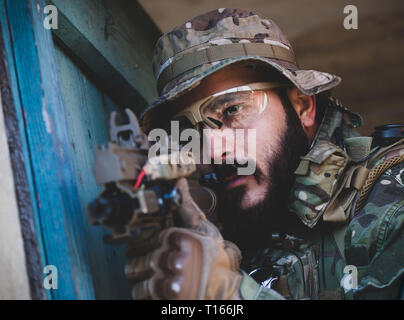 Airsoft military game player in camouflage uniform with armed assault rifle. Stock Photo