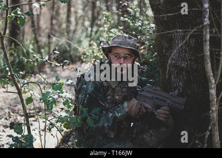 Airsoft military game player in camouflage uniform with armed assault rifle. Stock Photo