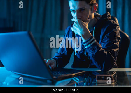 A young man working on a laptop at night. A freelancer is working late on a project at home. Stock Photo