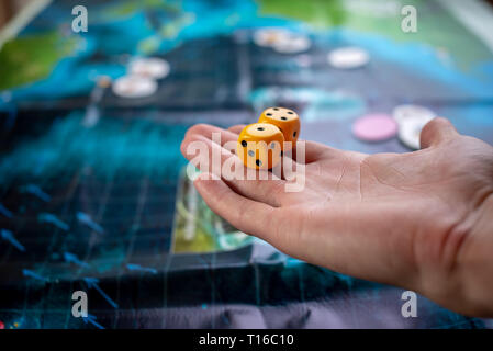The hand throws yellow dice on the playing field. Luck and excitement. Concept of Board games. Gaming moments in dynamics Stock Photo