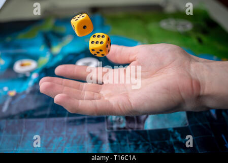 The hand throws two yellow dice on the playing field. Luck and excitement. The concept of Board games. Gaming moments in dynamics Stock Photo