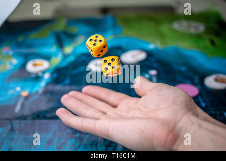 The hand throws two yellow dice on the playing field. Luck and excitement. The concept of Board games. Gaming moments in dynamics Stock Photo