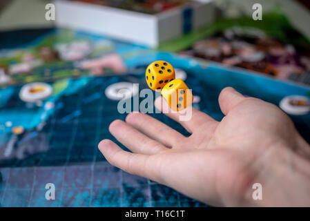 The hand throws yellow dice on the playing field. Luck and excitement. Concept of Board games. Gaming moments in dynamics Stock Photo