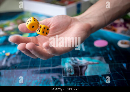 The hand throws two yellow dice on the playing field. Luck and excitement. The concept of Board games. Gaming moments in dynamics Stock Photo