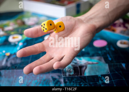 The hand throws yellow dice on the playing field. Luck and excitement. Concept of Board games. Gaming moments in dynamics Stock Photo