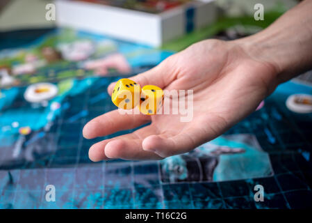 The hand throws two yellow dice on the playing field. Luck and excitement. The concept of Board games. Gaming moments in dynamics Stock Photo