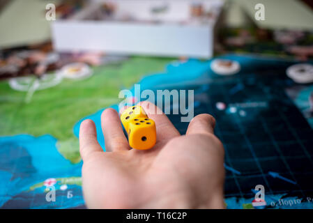 The hand throws two yellow dice on the playing field. Luck and excitement. The concept of Board games. Gaming moments in dynamics Stock Photo