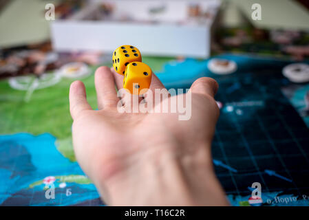 The hand throws yellow dice on the playing field. Luck and excitement. The concept of Board games. Gaming moments in dynamics Stock Photo