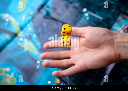 The hand throws two yellow dice on the playing field. Luck and excitement. The concept of Board games. Gaming moments in dynamics Stock Photo