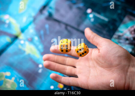 The hand throws two yellow dice on the playing field. Luck and excitement. The concept of Board games. Gaming moments in dynamics Stock Photo