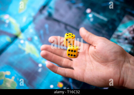 Hand throws the dice on the background of colorful blurred fantasy Board games, gaming moments in dynamics Stock Photo